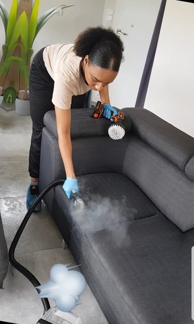 Technicienne C'propre nettoyant un canapé à la vapeur